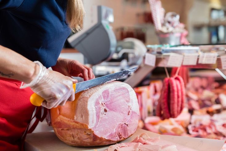 Person die in einer Fleischerei Fleisch schneidet